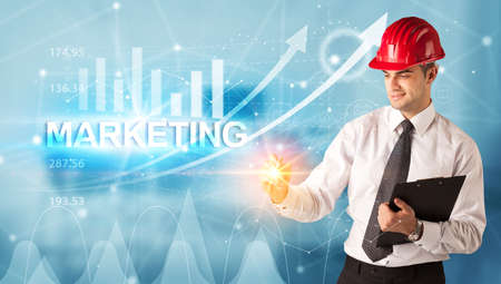 Young businessman with helmet drawing MARKETING inscription, modern business technology conceptの写真素材