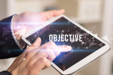 Close up hands using tablet with OBJECTIVE inscription, modern business technology conceptの写真素材