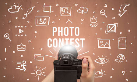 Hand taking picture with digital camera and PHOTO CONTEST inscription, camera settings conceptの写真素材