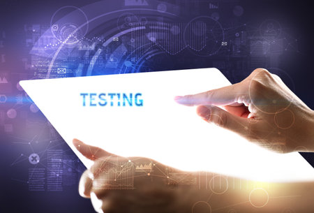 Hand holdig futuristic tablet with TESTING inscription, new technology conceptの写真素材