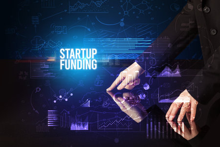 Businessman touching huge screen with STARTUP FUNDING inscription, cyber business conceptの写真素材