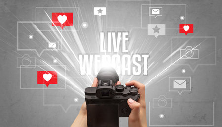 Close-up of a hand taking photos with LIVE WEBCAST inscription, social media conceptの写真素材