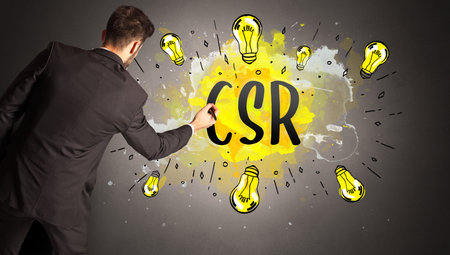 businessman drawing colorful light bulb with CSR abbreviation, new technology idea conceptの写真素材