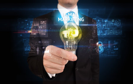 Businessman holding lightbulb with E-MAIL MARKETING inscription, online security idea conceptの写真素材