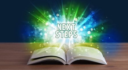 NEXT STEPS inscription coming out from an open book, educational concept