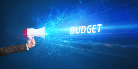 Young person shouting in loudspeaker with BUDGET inscription, business concept