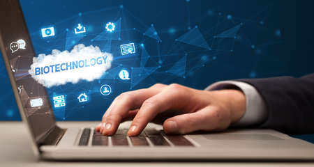 Businessman working on laptop with BIOTECHNOLOGY inscription, modern technology conceptの写真素材