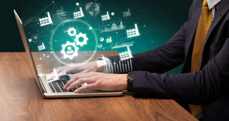 Business hand working on laptop with gear icons coming out from the screen, successful business conceptの写真素材