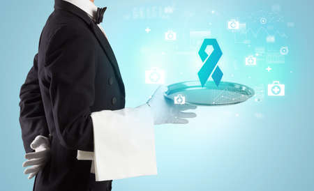 Handsome young waiter in tuxedo holding healthcare icons on trayの写真素材