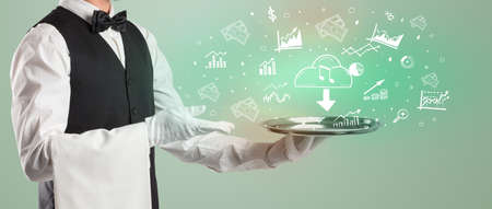 Handsome young waiter in tuxedo holding money icons on trayの写真素材