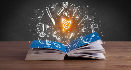Open recipe book with food related icons aboveの写真素材