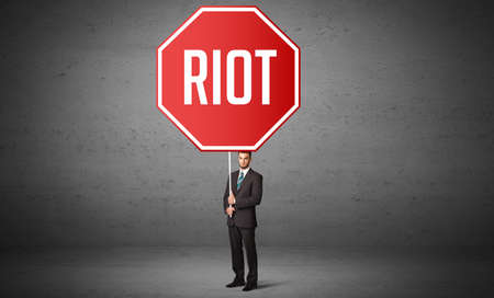 Young business person holding road signの写真素材