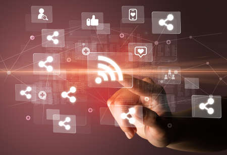 Hand pressing social media multimedia application screen with media icons on futuristic concept