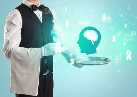 Handsome young waiter in tuxedo holding healthcare icons on trayの写真素材