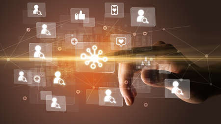 Hand pressing social media multimedia application screen with media icons on futuristic conceptの写真素材