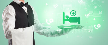 Handsome young waiter in tuxedo holding healthcare icons on trayの写真素材