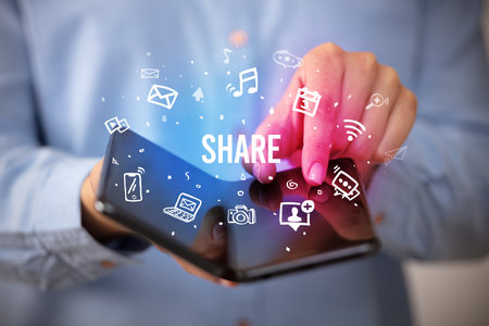 Businessman holding a foldable smartphone, social media conceptの写真素材