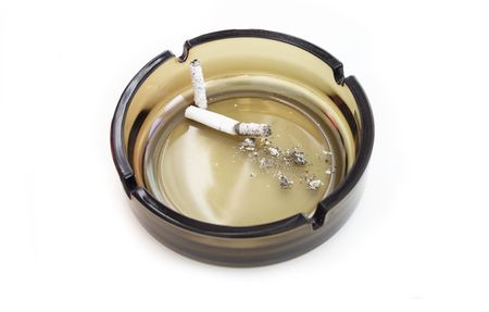 Ashes from a cigarette in an ashtray from dark glass. A white background.