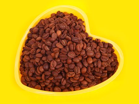 Coffee beans in the bowl in the form of heart. Yellow background. の写真素材