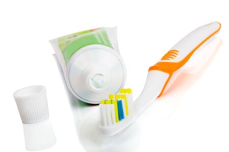 Toothbrush and open tube of toothpaste on a white background. Soft shadow