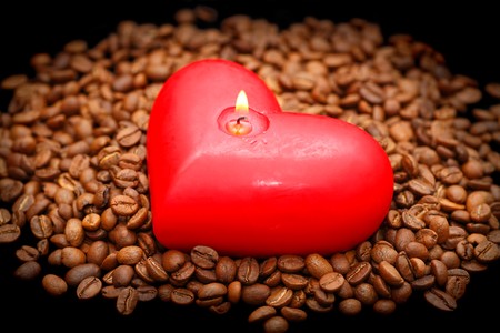 Coffee beans in the light of red candles on a black backgroundの写真素材
