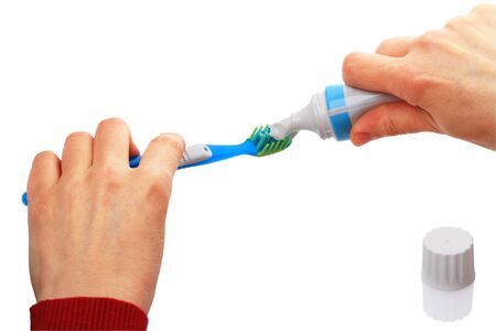 Toothbrush and open tube of toothpaste on a white background. 