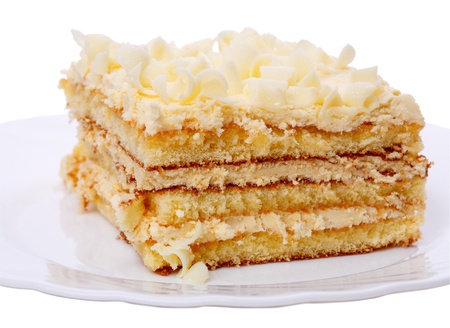 Piece of cake with cream on white plate. Isolated on a white background.