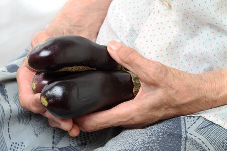 An old woman with three eggplant in her hands.の写真素材