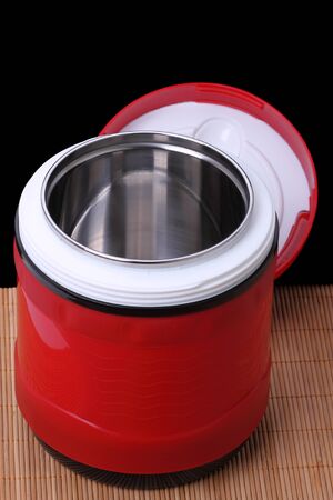 Modern thermos for food with a metal bulb isolated on a black backgroundの写真素材