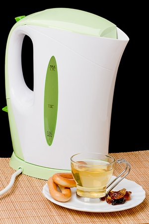 Modern plastic kettle and a cup of tea with dark sugar and bagelの写真素材