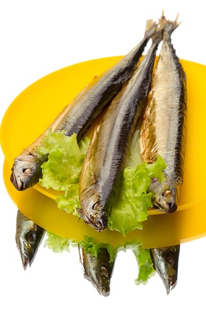Three smoked saury on yellow plate isolated on white background	の写真素材