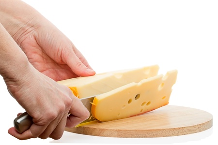 Cutting cheese with a kitchen knife on a cutting board isolated on white backgroundの写真素材