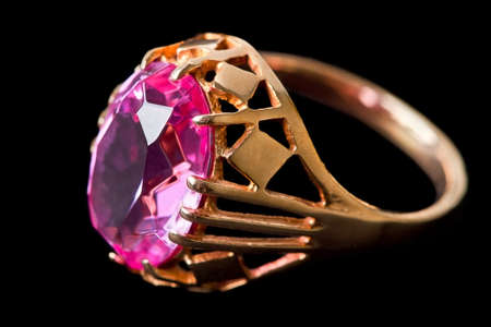 Gold ring with pink stone isolated on a black backgroundの写真素材