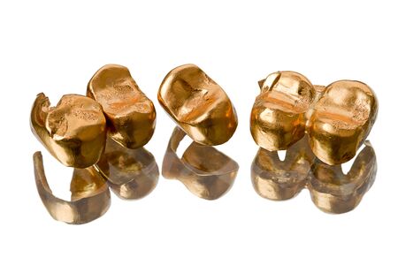 Gold dental crowns (prosthetic teeth) isolated on white backgroundの写真素材