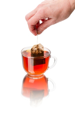 The hand with the teabag and a cup of hot tea. Isolated on white backgroundの写真素材
