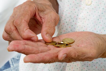 Hands of an old woman with five coinsの写真素材