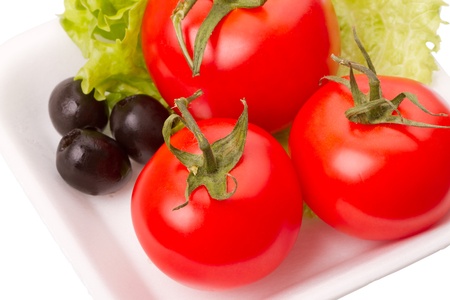 Tomatoes and olives on the lettuce leaf on white backgroundの写真素材