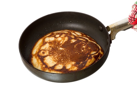 Hot pancake in a frying pan isolated on white backgroundの写真素材