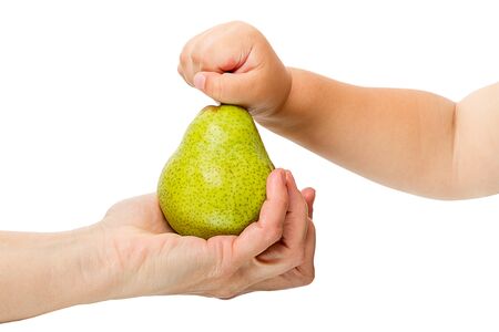 Woman's hand gives the child a ripe pear. Isolated on white backgroundの写真素材