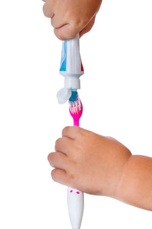 Hand the child does toothpaste on toothbrush. Isolated on white backgroundの写真素材