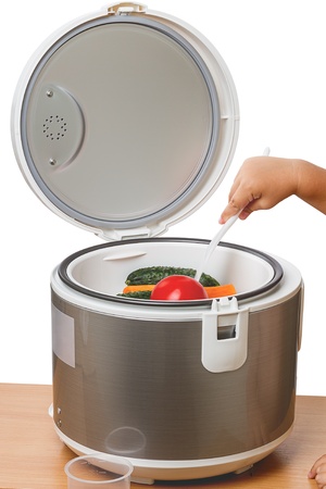 Electric steamer with vegetables and a child with a spoonの写真素材