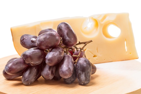 Cheese and dark grapes on the cutting board isolated on white backgroundの写真素材
