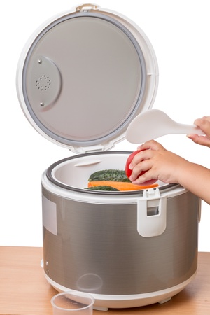 Electric pressure cooker  with vegetables and a child with a spoonの写真素材