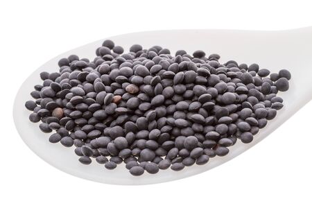 Black lentils in a plastic spoon isolated on white backgroundの写真素材