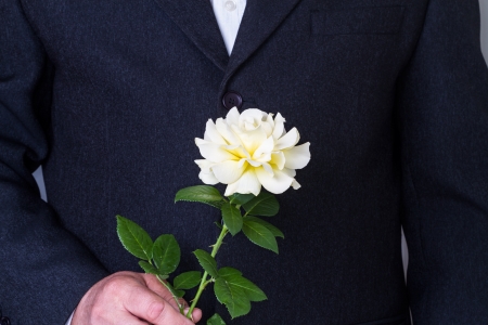 A man in a black suit with a white roseの写真素材