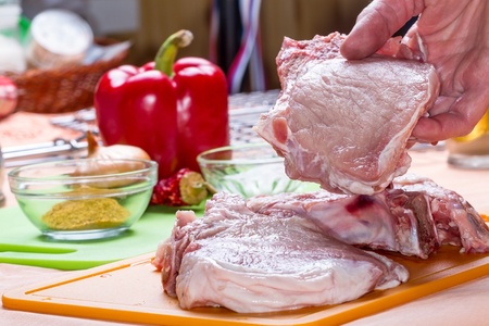 Fresh meat on a cutting board and in handの写真素材