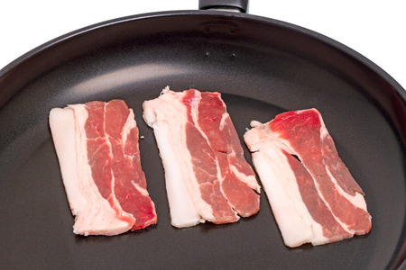 Three slices of bacon in a frying panの写真素材