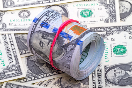Hundred dollar roll up with red rubber on dollars backgroundの写真素材