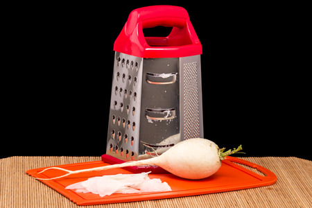 Pile of grated daikon  radish and grater on kitchen boardの写真素材