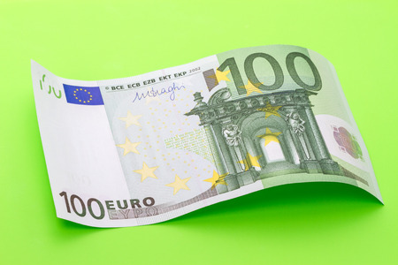 A wave of bank notes hundred euros on a green backgroundの写真素材